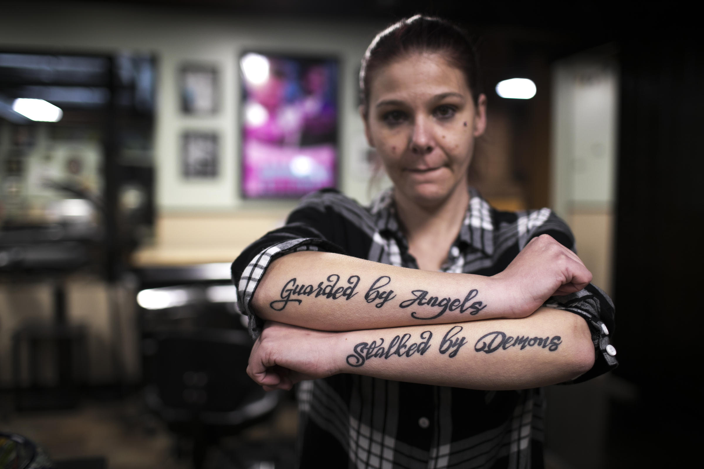 Jenn Glaser shows off her arm tattoos. They say 'guarded by angels, stalked by demons.'